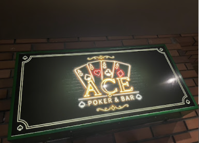 ACEの入口を案内する、レンガ壁に掲げられた光る看板